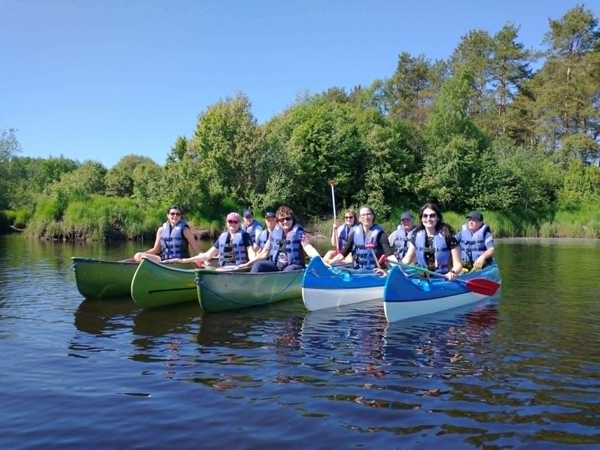 Purolomat_viisi kanoottia rinta rinnan melojineen joella.