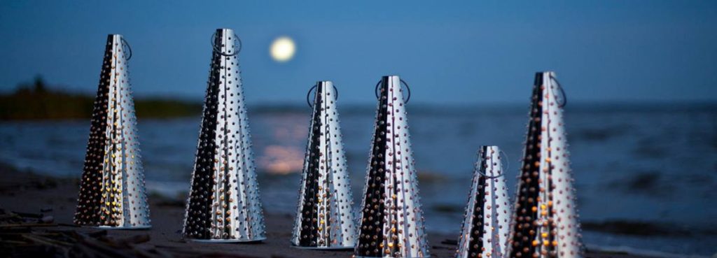 Taito Shopin pläkkilyhdyt kuutamon valossa, meritaustalla.