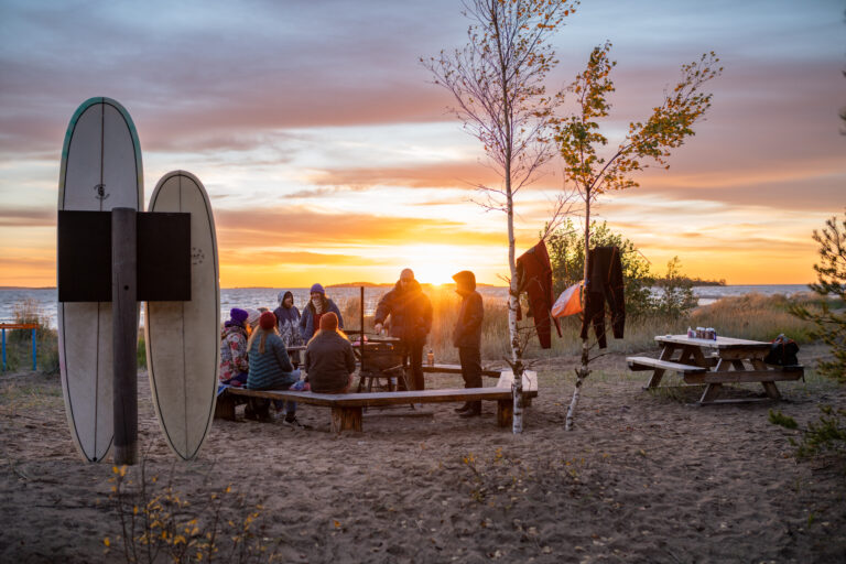 Ihmisiä Munakarin nuotiopaikalla auringonlaskun aikaan