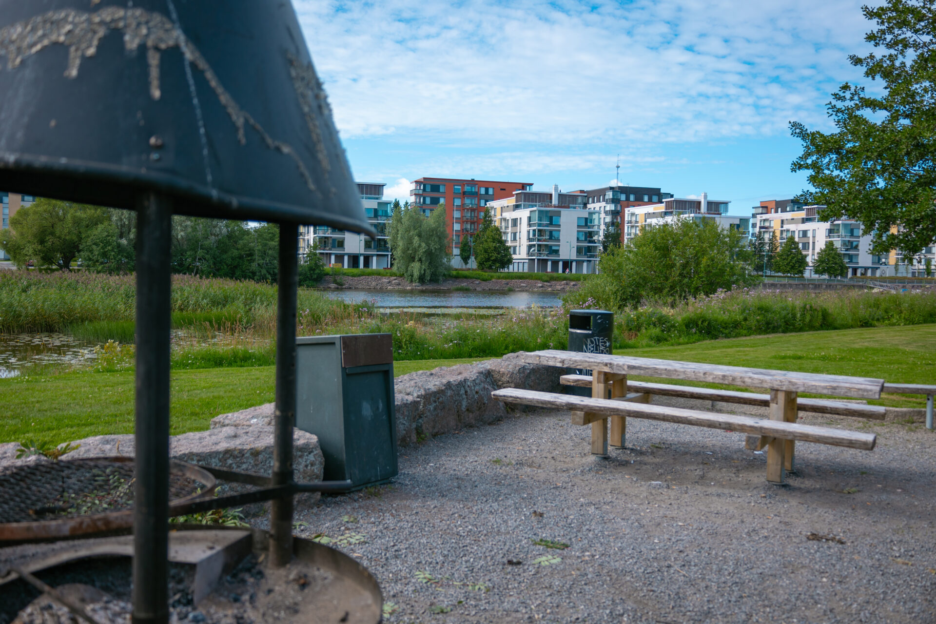 grillauspaikka joen varrella, joen toisella puolella kerrostaloja