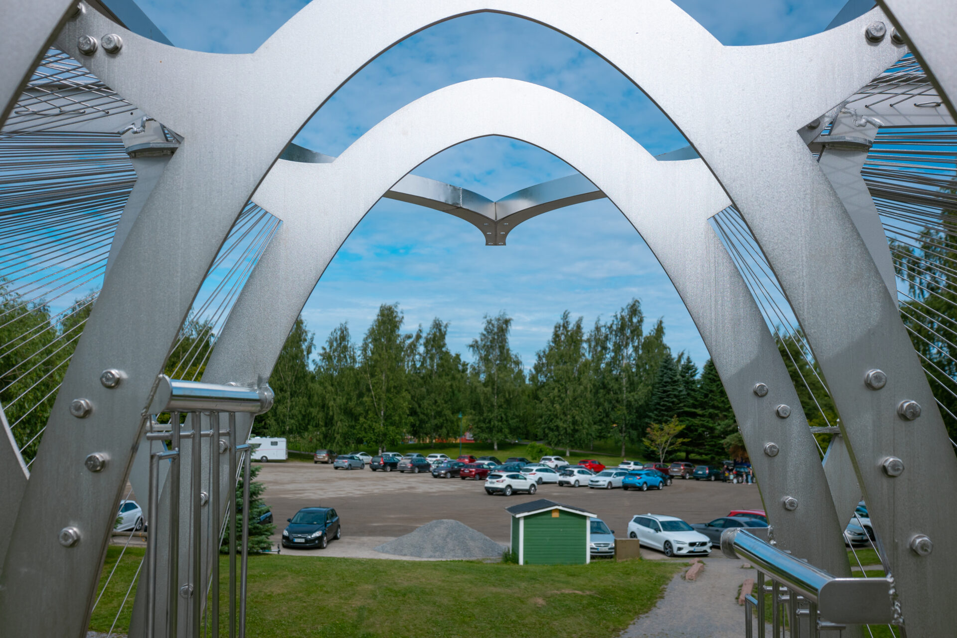 parkkipaikka jossa autoja, taustalla puita