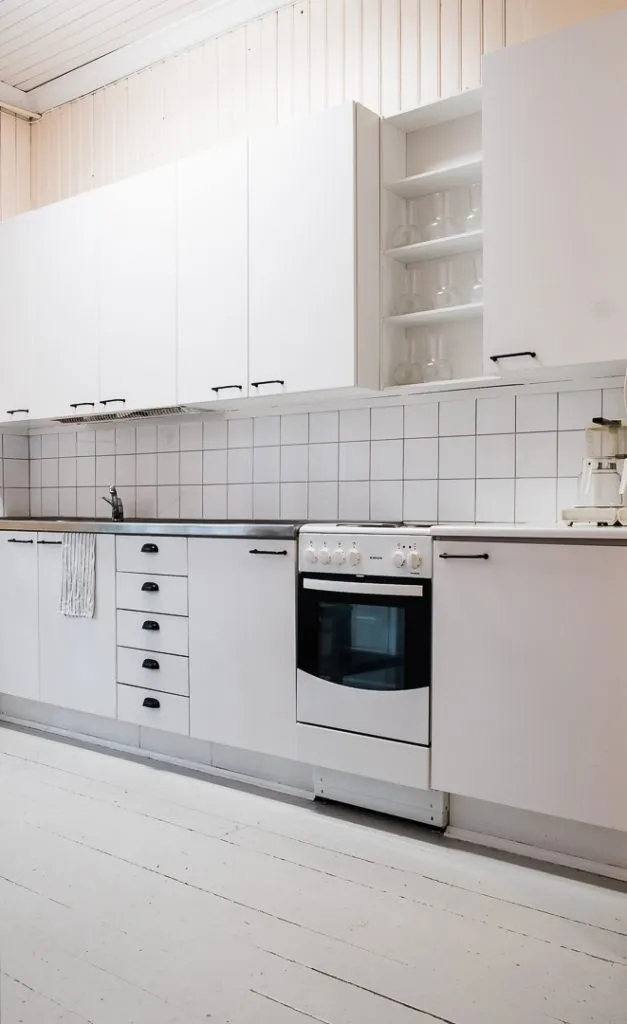 vaalea keittiö jossa valkoiset kaapistot ja uuni, pöydällä kahvinkeitin