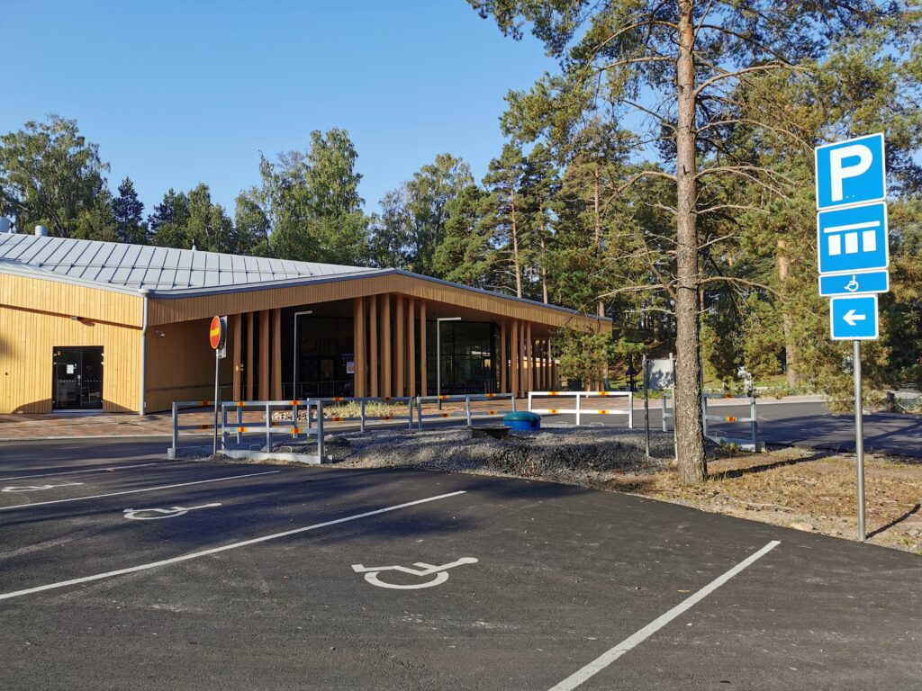 Parking spaces marked as accessible, with trees and a timber-framed building in the background
