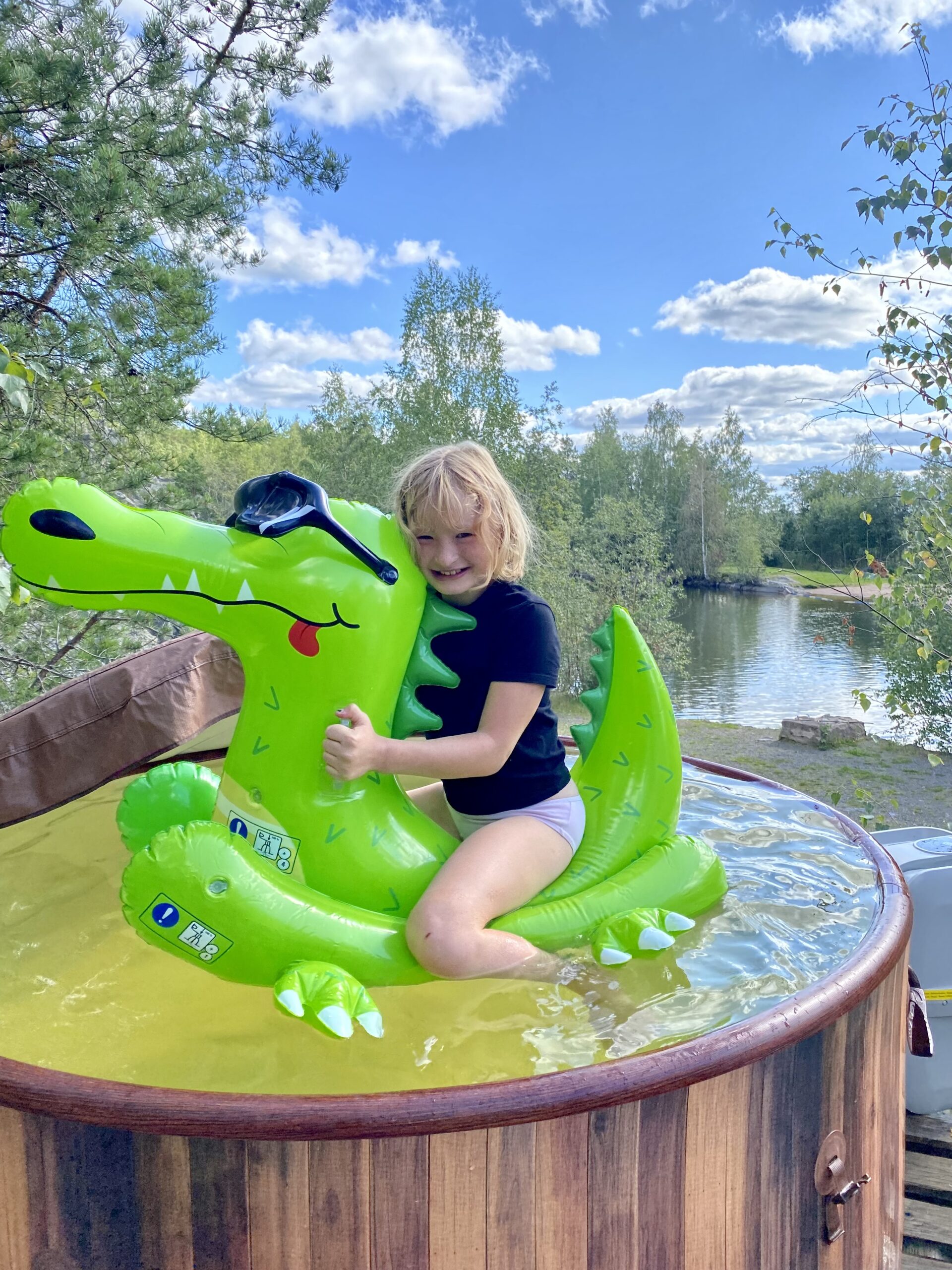 FinnDome glampingalueella myös palju jossa iloinen lapsi kelluu muovilelun kanssa.