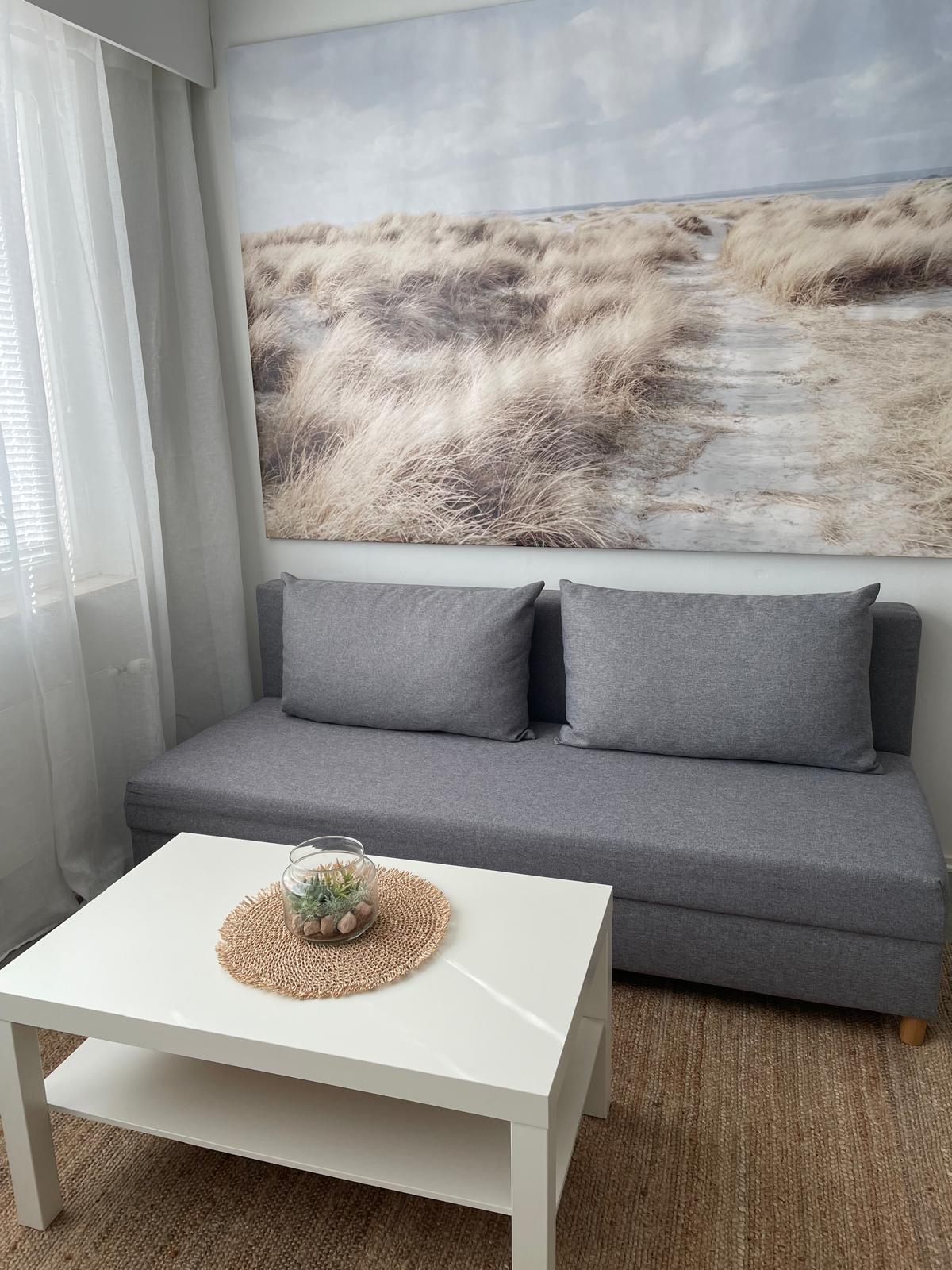 Loma-asunto Beach House Yyterin olohuoneen sohva ja iso merimaisemataulu seinällä