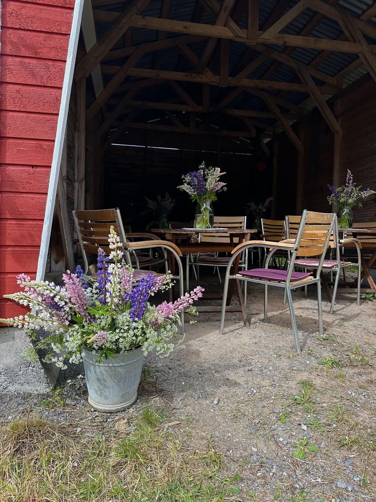 Venlan Pirttikahvilan miljöön pöytiä ja tuoleja kukkien kera