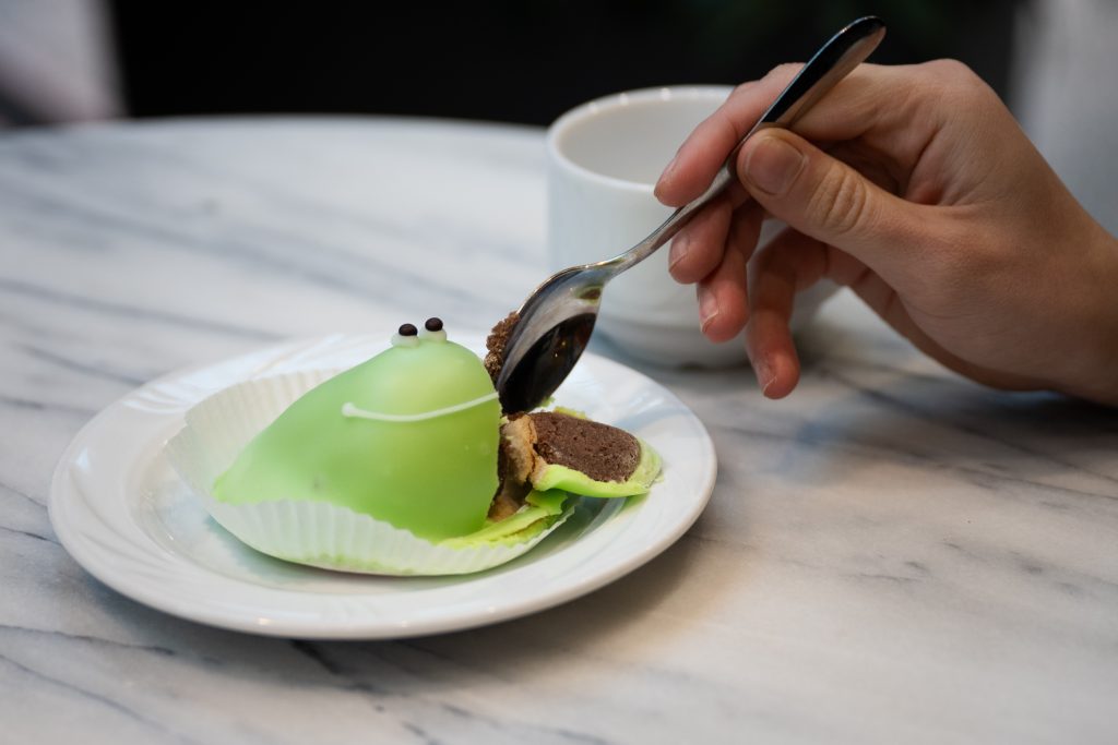 Vihreästä sammakkoa muistuttavasta leivonnaisesta lohkaistaan palaa.