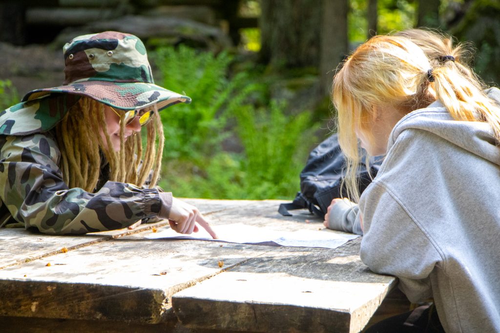 Henkilökt tarkastelemassa karttaa taukopaikan pöydän ääressä.