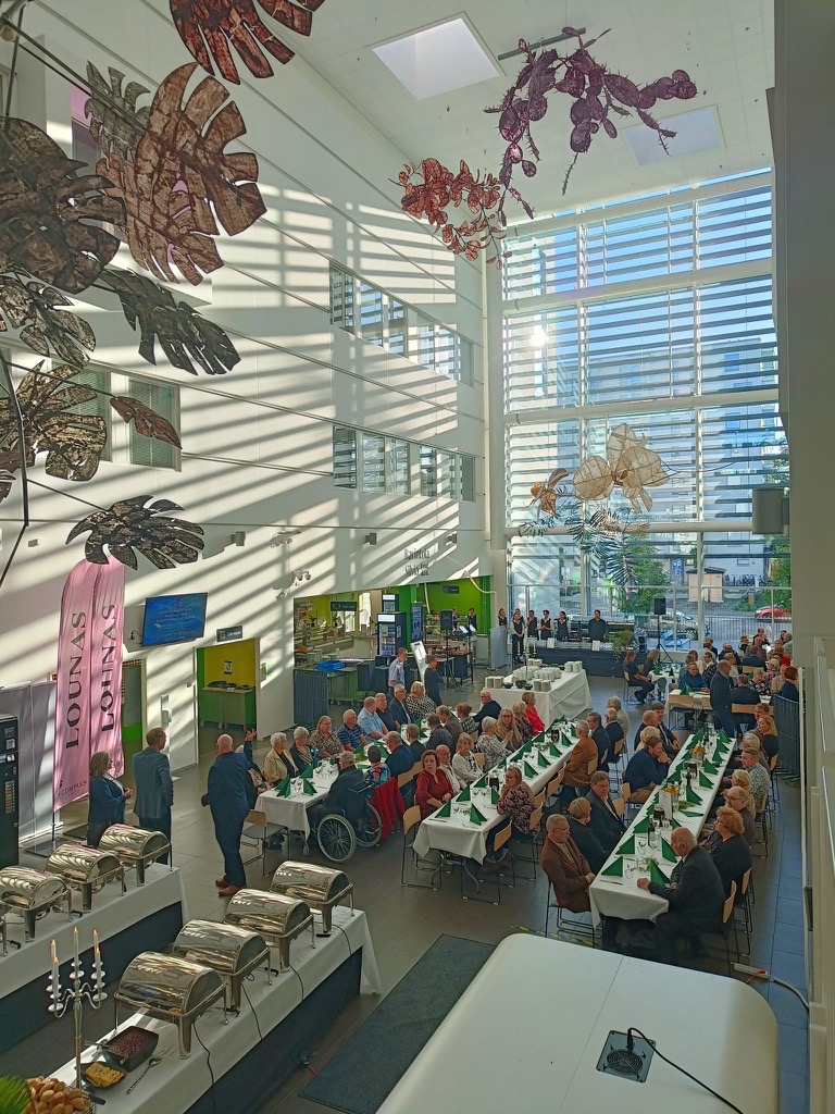 Ravintola Silvia_tilassa ihmisiä pitkissä pöydissä ja buffeepöytä valmiina.