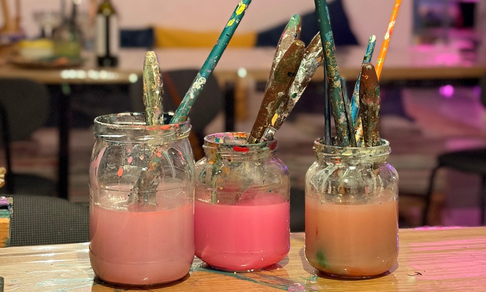 Luavaamossa maalausvälineitä vesipurkeissa, joissa värillistä vettä.