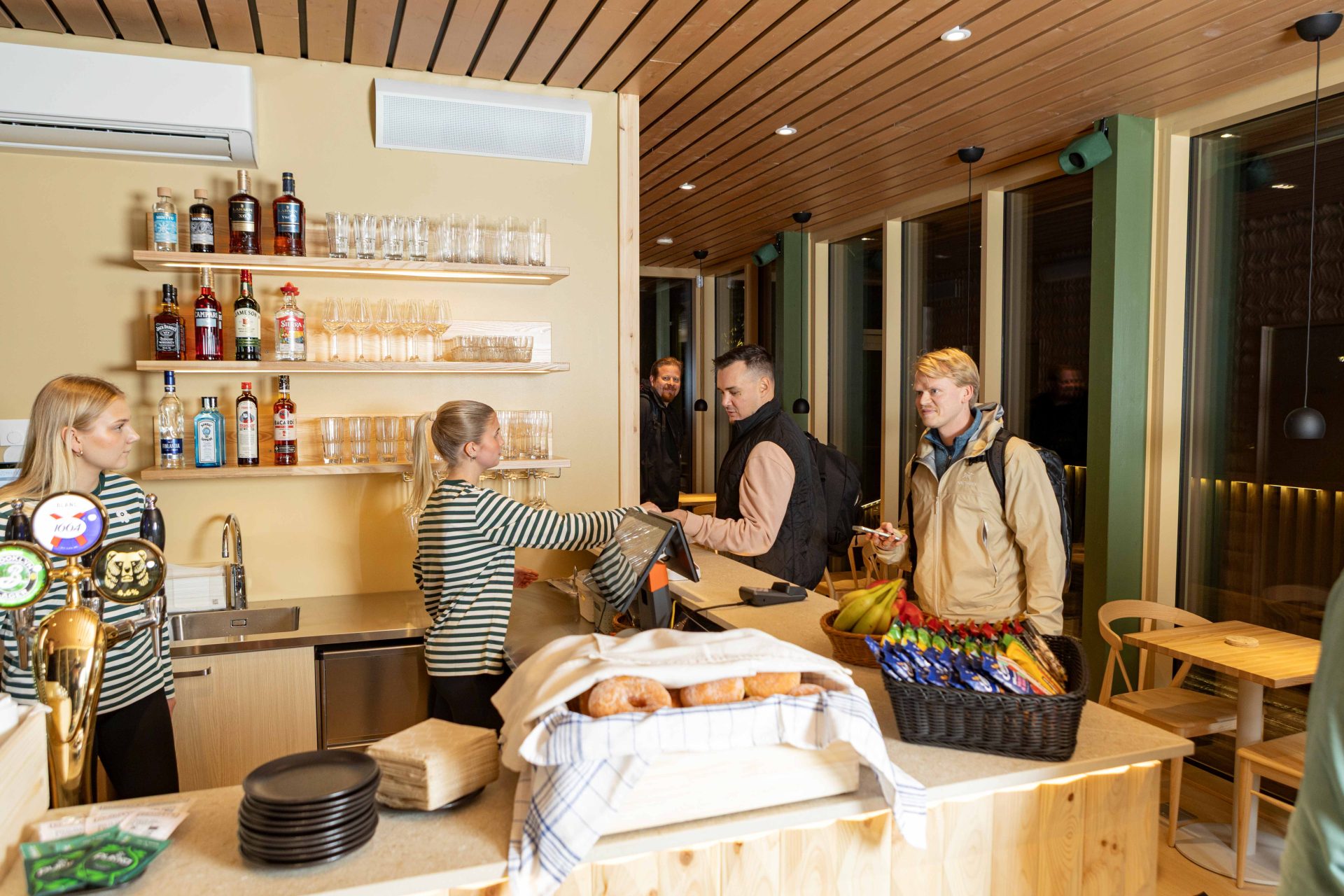 Rauha Sauna & Loungen kahvilan palvelutiskillä asiakkaita.