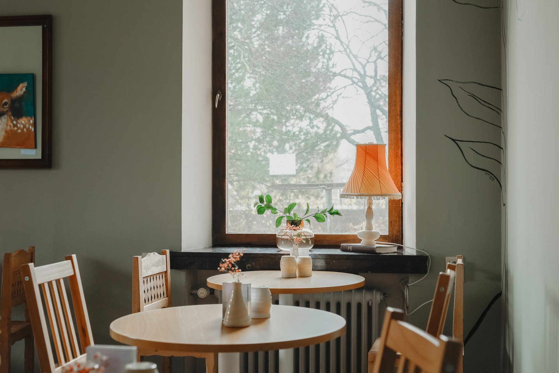 Teelempi teehuoneen pöytiä ja ikkuna, jossa lamppu.