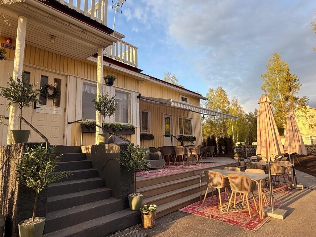 Keltainen Villa Rouhee ulkoa terasseineen ja terassikalusteineen.